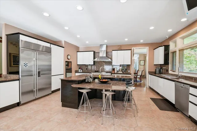 a kitchen with stainless steel appliances granite countertop table chairs sink refrigerator and cabinets