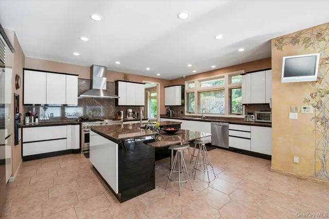 a kitchen with stainless steel appliances granite countertop a stove top oven a sink dishwasher a refrigerator and white cabinets with wooden floor