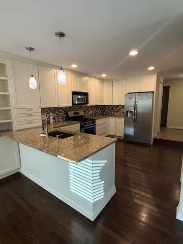 a kitchen with stainless steel appliances granite countertop a sink a stove top oven a counter space and cabinets