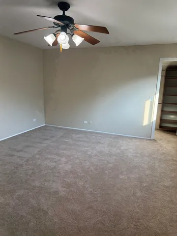 a view of an empty room with a chandelier fan