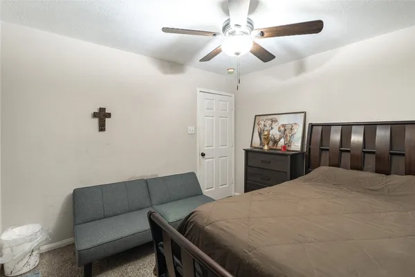 a bedroom with a bed ceiling fan and a wooden floor
