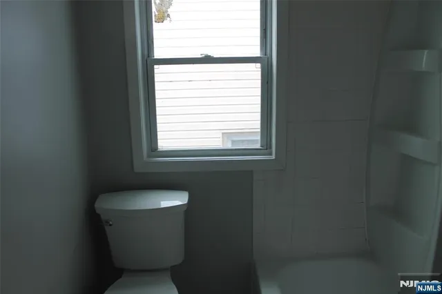 a white toilet sitting in a bathroom next to a window