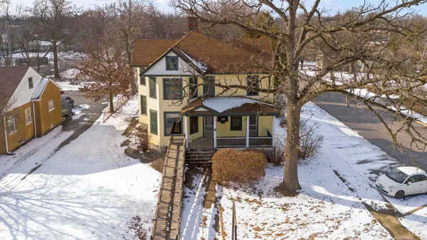 a front view of a house with a yard covered with snow