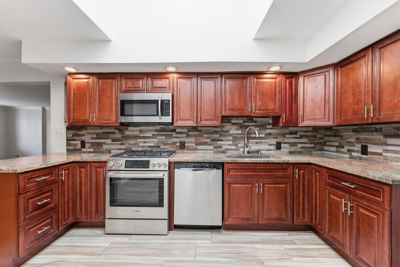 229 Centre Avenue Secaucus, NJ 07094 - Photo 10 of 40 a kitchen with stainless steel appliances granite countertop wooden cabinets and a stove top oven