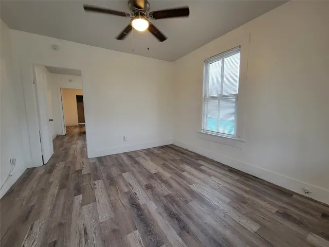 an empty room with wooden floor cabinet and windows
