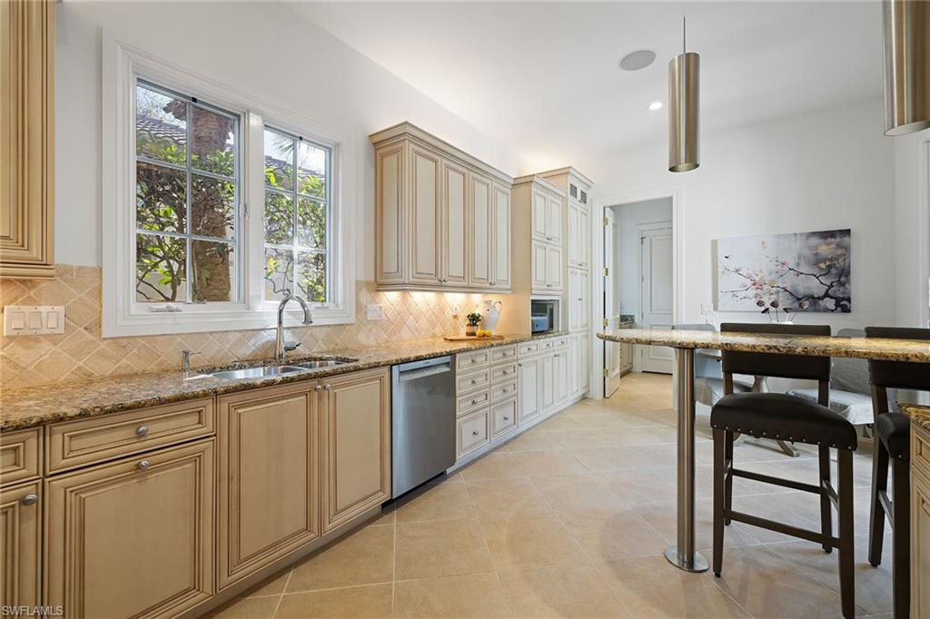 15655 Villoresi Way Naples, FL 34110 - Photo 13 of 47 a kitchen with granite countertop sink window and chairs
