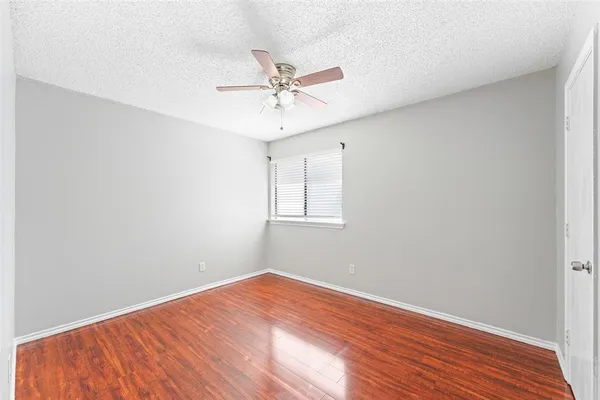 an empty room with wooden floor fan and windows