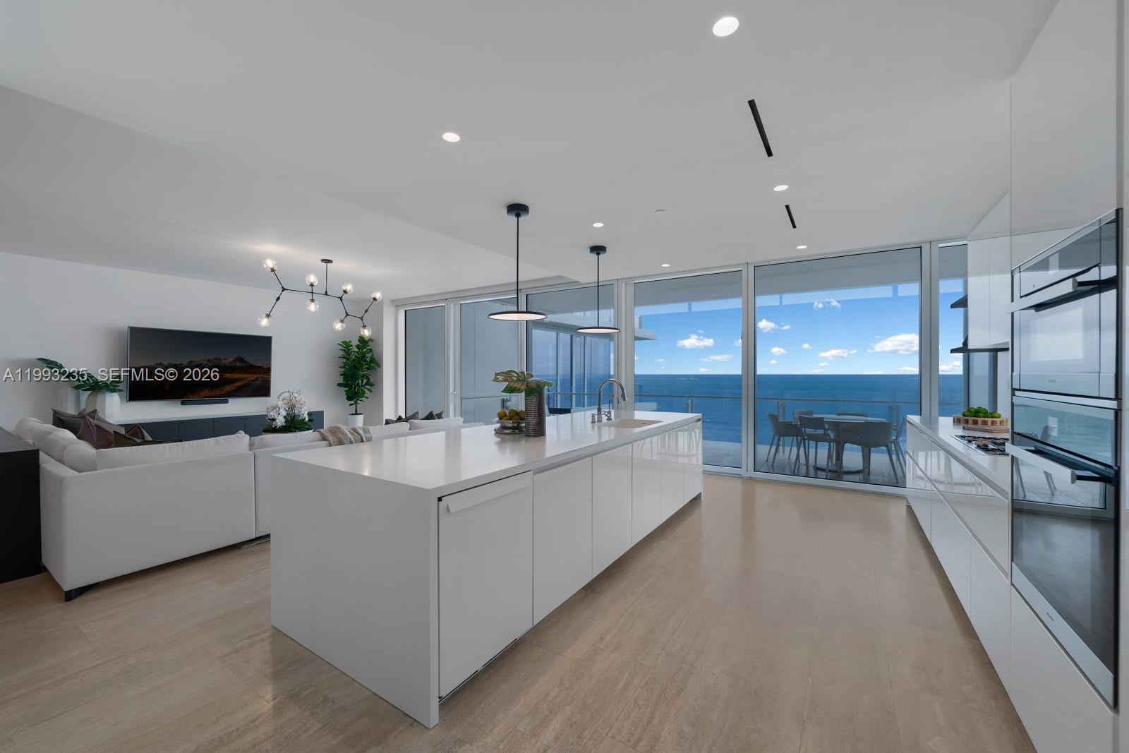 9111 Collins Avenue, Unit N717 Surfside, FL 33154 - Photo 7 of 68 a large white kitchen with kitchen island a large counter top space a sink and stainless steel appliances