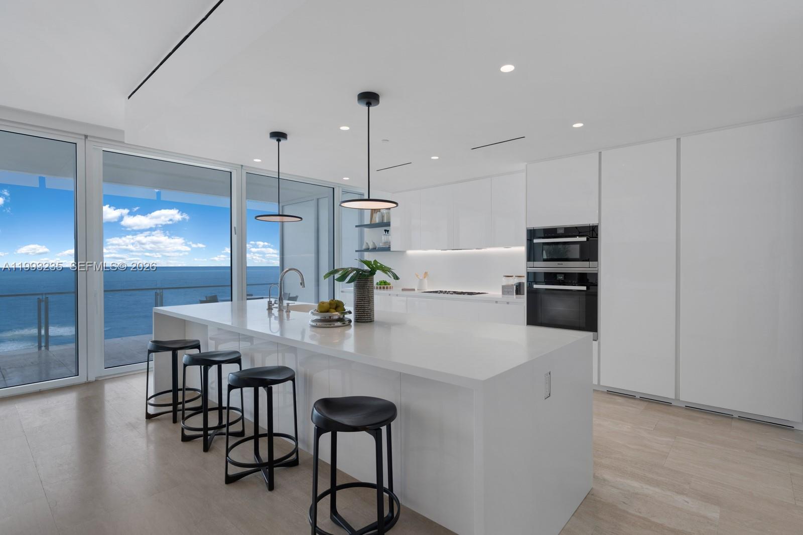9111 Collins Avenue, Unit N717 Surfside, FL 33154 - Photo 9 of 68 a kitchen with stainless steel appliances a table chairs and wooden floor