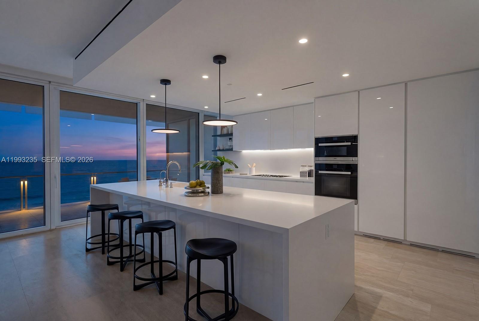 9111 Collins Avenue, Unit N717 Surfside, FL 33154 - Photo 10 of 68 a kitchen with stainless steel appliances kitchen island granite countertop a table chairs sink and wooden floor