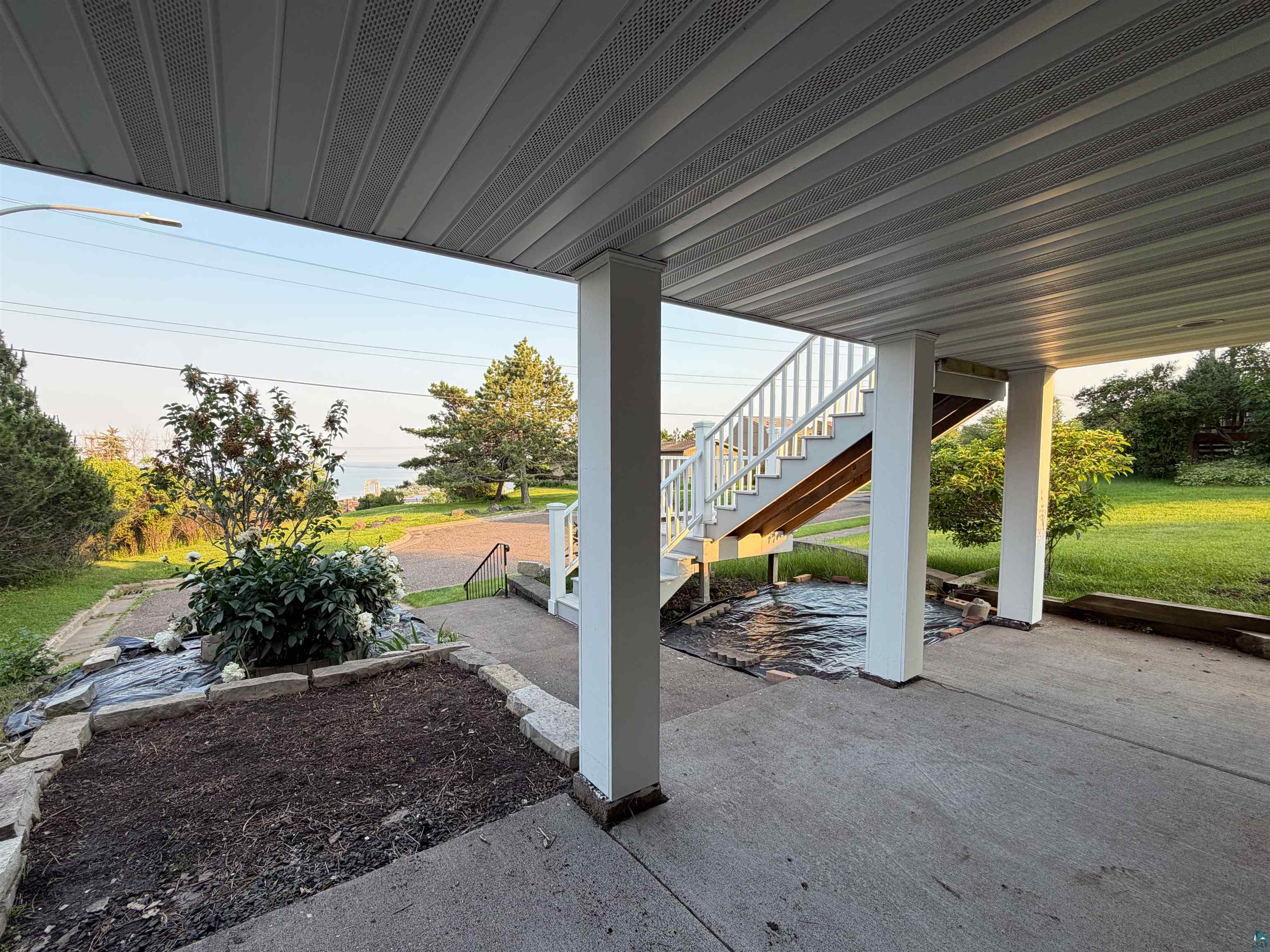 13 West 8th Street Duluth, MN 55806 - Photo 55 of 57 Covered concrete patio space featuring white support columns and a painted wood staircase