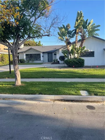 a front view of a house with a yard and large trees