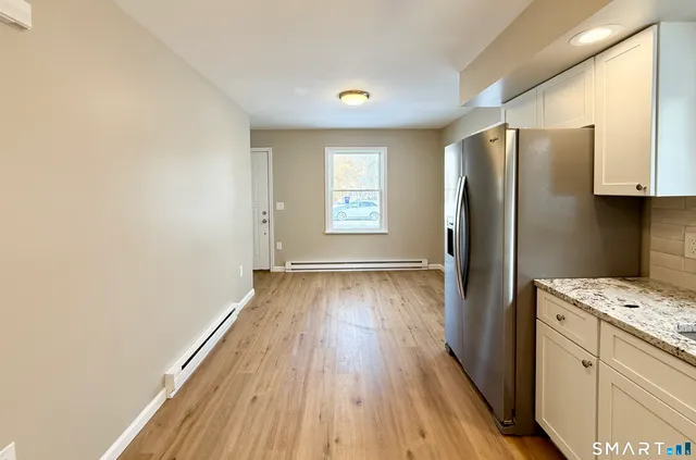 a kitchen with a refrigerator and wooden floor