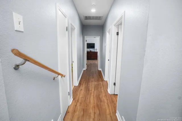 a view of a hallway with wooden floor and staircase