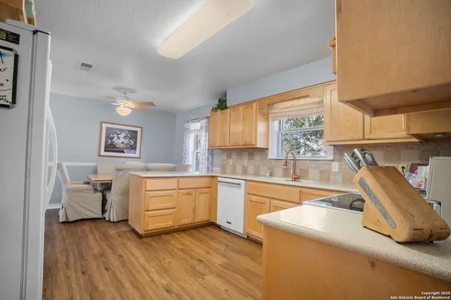 a kitchen with granite countertop a sink and white cabinets with wooden floor