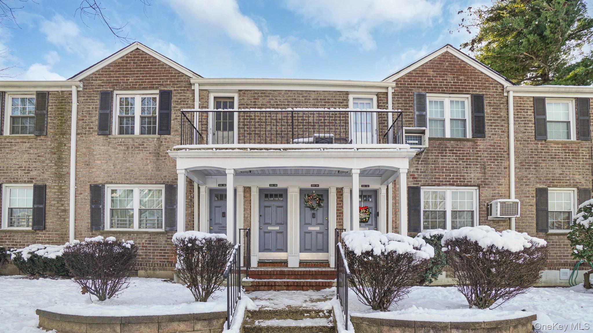 View of front facade featuring brick siding, covered porch, and a balcony