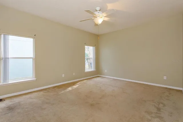 an empty room with windows and ceiling fan