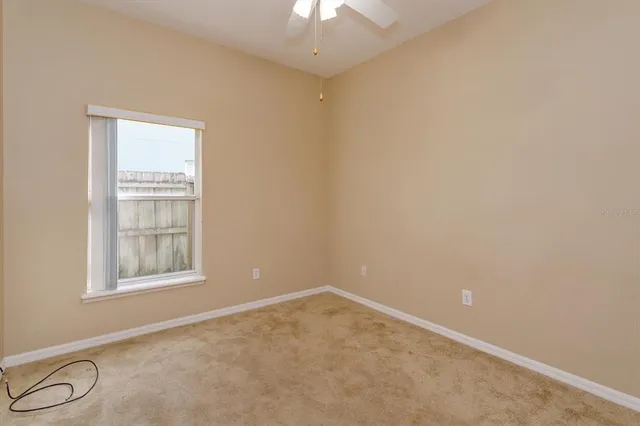 an empty room with a window and a fan