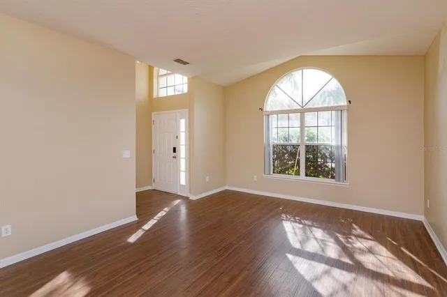 an empty room with wooden floor and windows