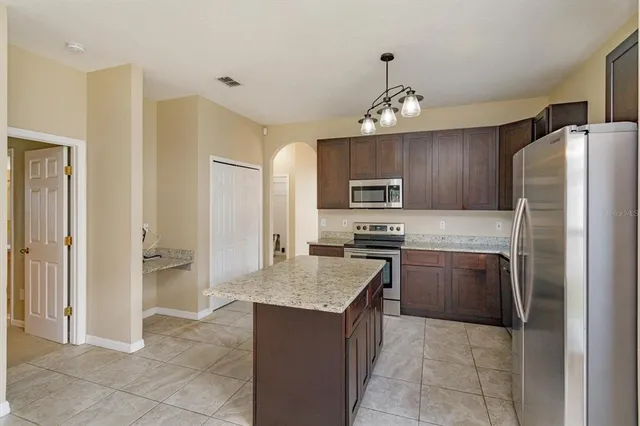 a kitchen with granite countertop stainless steel appliances a stove refrigerator and microwave