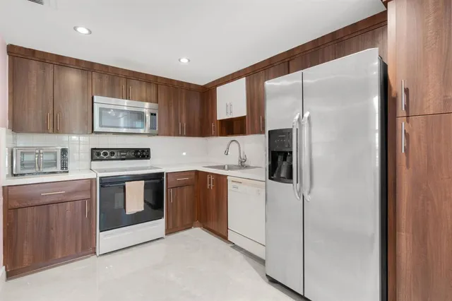 a kitchen with stainless steel appliances granite countertop a refrigerator and a stove top oven