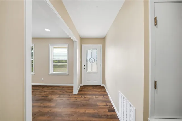 a view of hallway with window and wooden floor