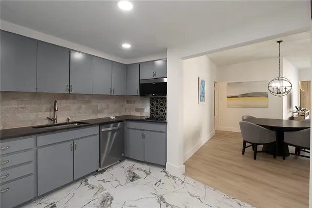 a kitchen with kitchen island granite countertop a sink cabinets and stainless steel appliances