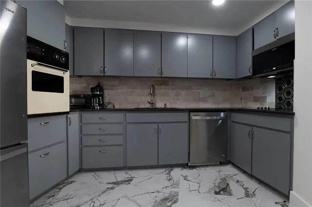 a kitchen with granite countertop white cabinets and stainless steel appliances
