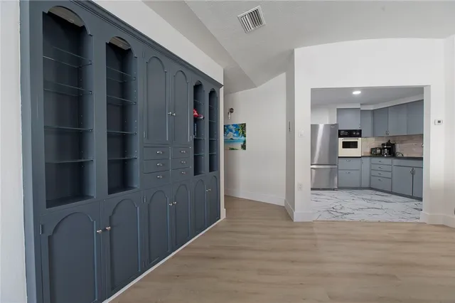 a view of a hallway with wooden floor and a kitchen