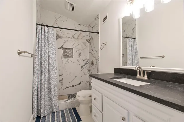 a bathroom with a granite countertop sink toilet and shower