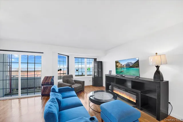 a living room with couches and a flat screen tv with kitchen view