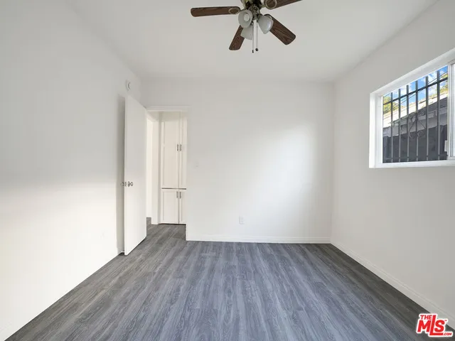 a view of empty room with wooden floor and fan