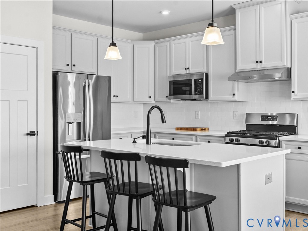 6230 Sheehan Crossing Moseley, VA 23120 - Photo 10 of 32 a kitchen with stainless steel appliances granite countertop a stove a refrigerator a microwave a island with white cabinets and wooden floor