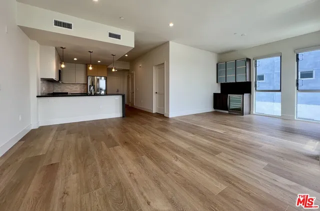 a view of kitchen and empty room with wooden floor