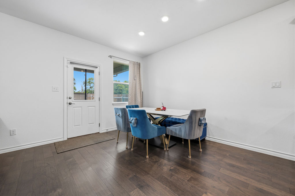205 Stinchcomb Road Hutto, TX 78634 - Photo 16 of 29 Rich hardwood floors complement the bright, open dining area, featuring a modern table and access to outdoor living.