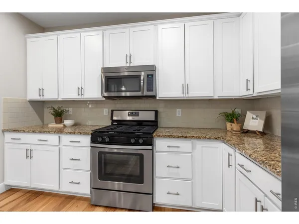 a kitchen with granite countertop white cabinets and appliances
