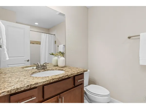 a bathroom with a granite countertop sink toilet and mirror