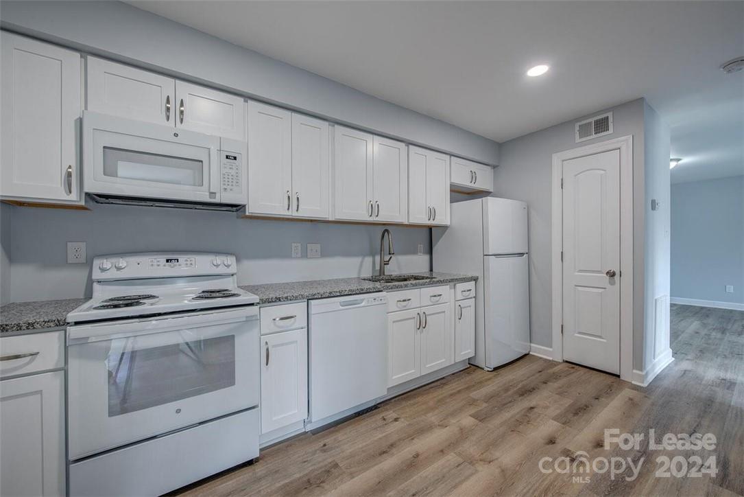 1024 Avondale Road, Unit 4 Lowell, NC 28098 - Photo 7 of 11 a kitchen with granite countertop white cabinets and white appliances