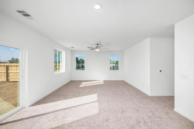 an empty room with windows and chandelier fan