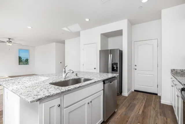 a kitchen with granite countertop a sink and refrigerator
