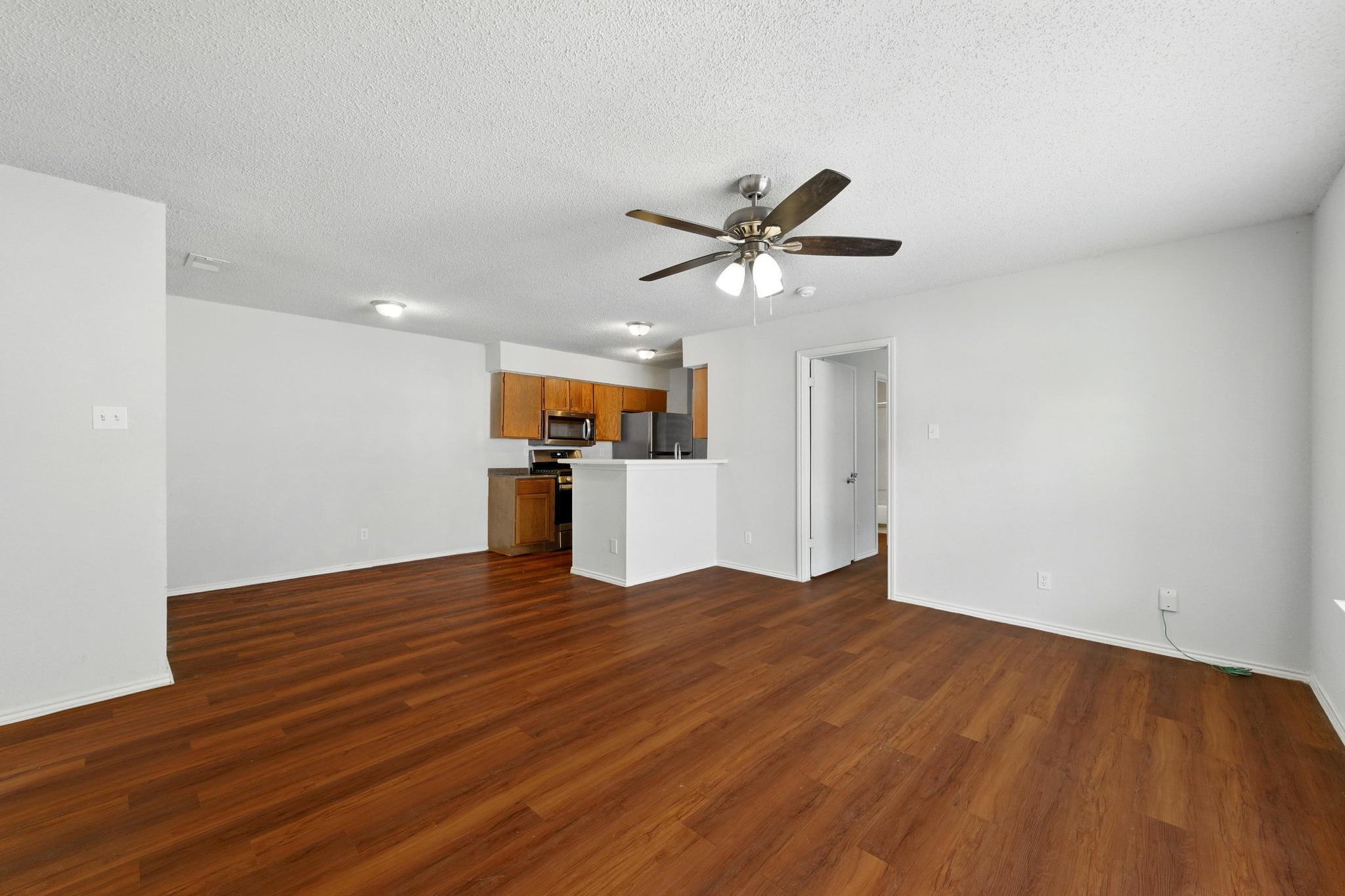 5707 Spring Meadow Road Austin, TX 78744 - Photo 6 of 21 a view of a big room with wooden floor and a kitchen