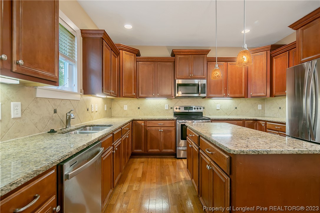 32 Shellnut Circle Spring Lake, NC 28390 - Photo 19 of 50 a kitchen with stainless steel appliances granite countertop a stove a sink dishwasher and a refrigerator with wooden cabinets