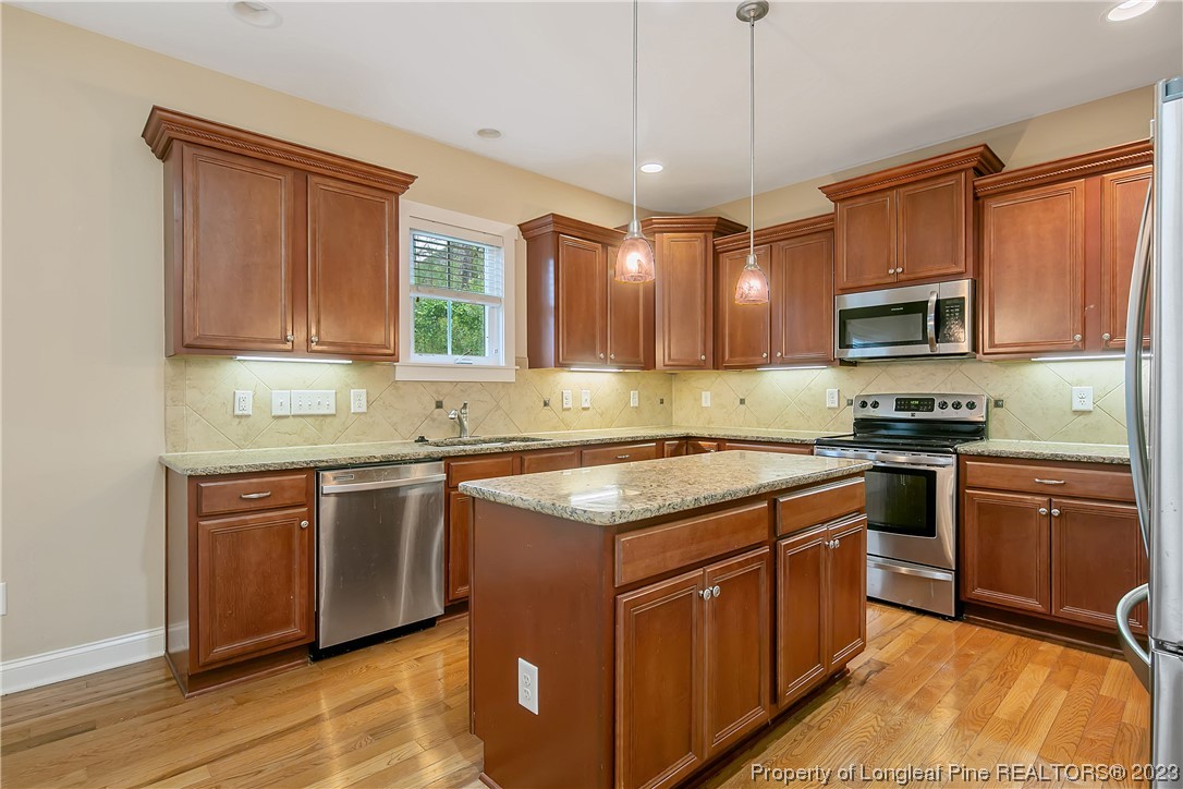32 Shellnut Circle Spring Lake, NC 28390 - Photo 20 of 50 a kitchen with stainless steel appliances granite countertop a stove a sink dishwasher and a microwave oven with wooden cabinets