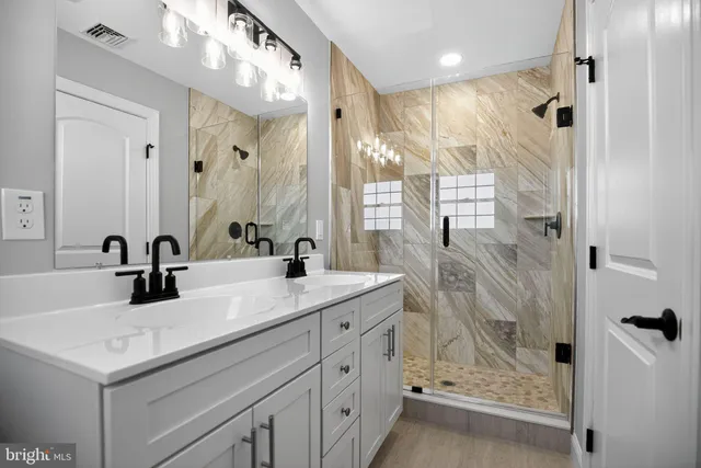 a bathroom with a shower sink vanity and mirror