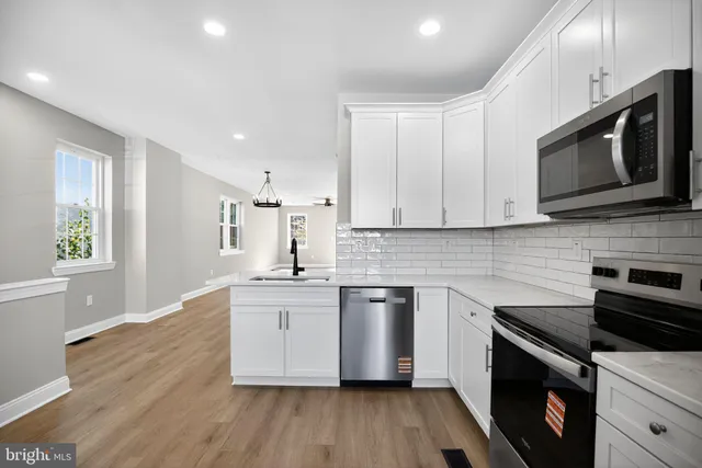 a kitchen with stainless steel appliances granite countertop a stove a sink dishwasher and a microwave oven with wooden floor