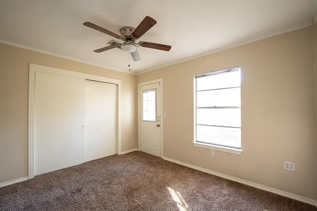 a view of a livingroom with a ceiling fan & windows