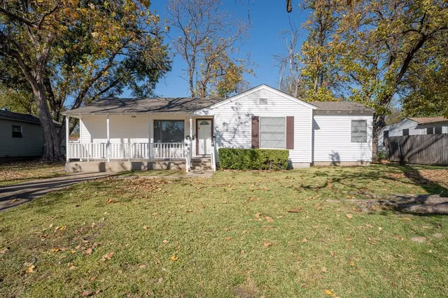 a view of a house with a yard and large tree
