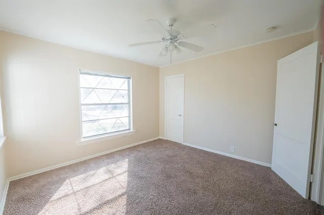 an empty room with a ceiling fan and window