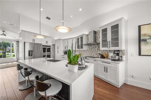 a kitchen with stainless steel appliances granite countertop a stove a sink dishwasher a dining table and chairs with wooden floor