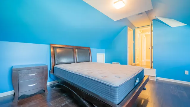 a bedroom with a bed and a dresser with wooden floor